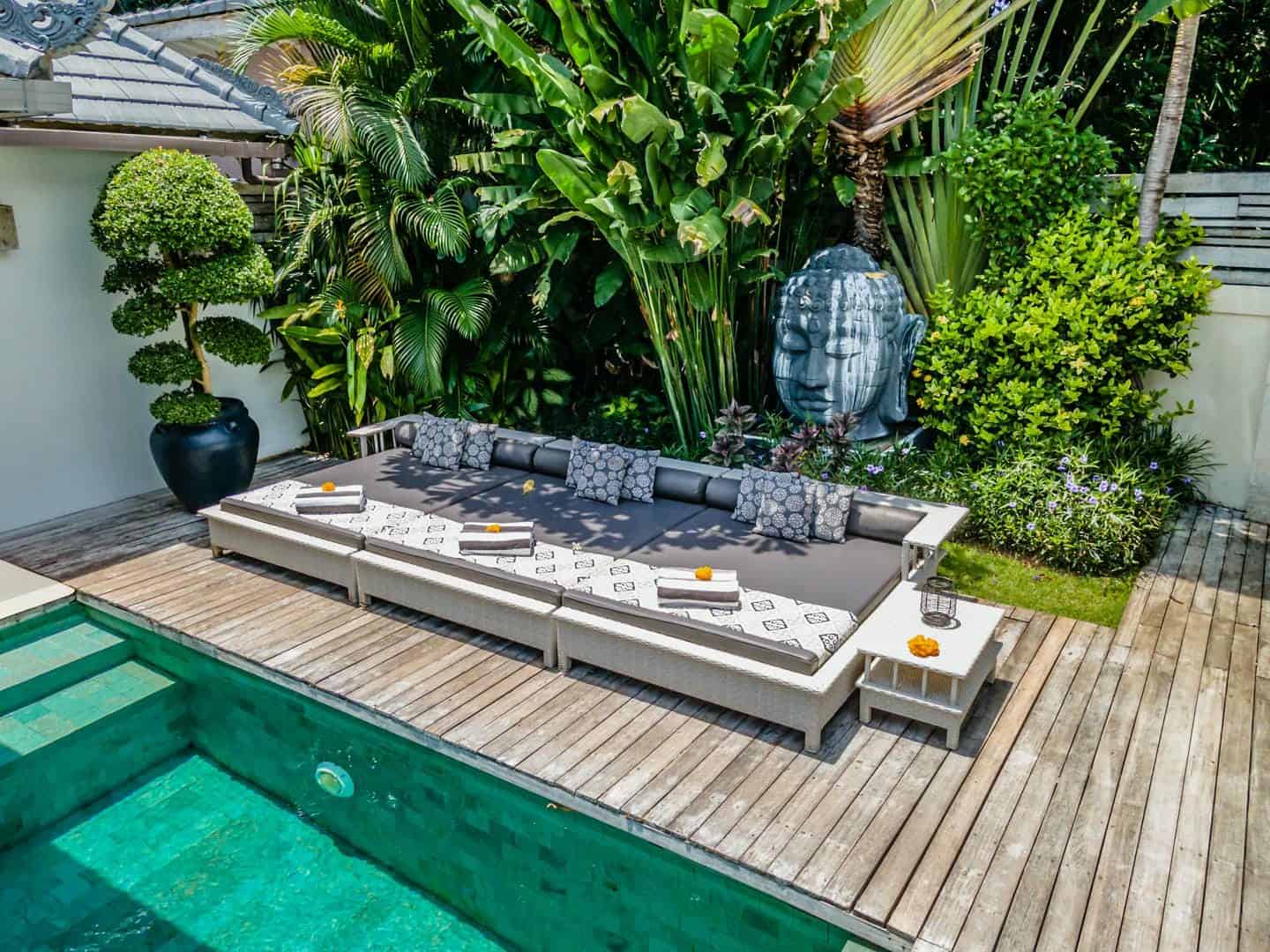 Tropical poolside lounge area with Buddha statue.