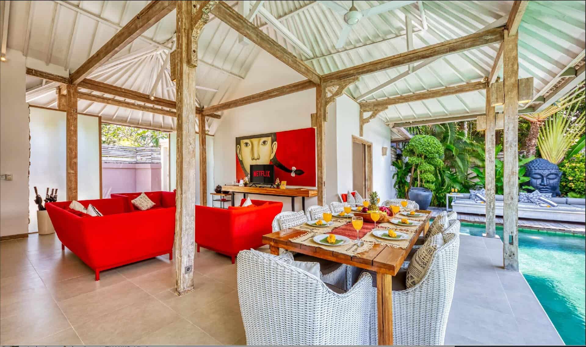 Tropical villa with pool and red sofas.
