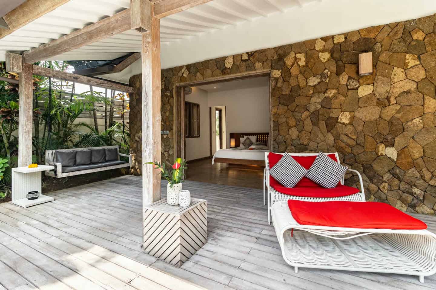 Tropical patio with lounge chairs and swing.