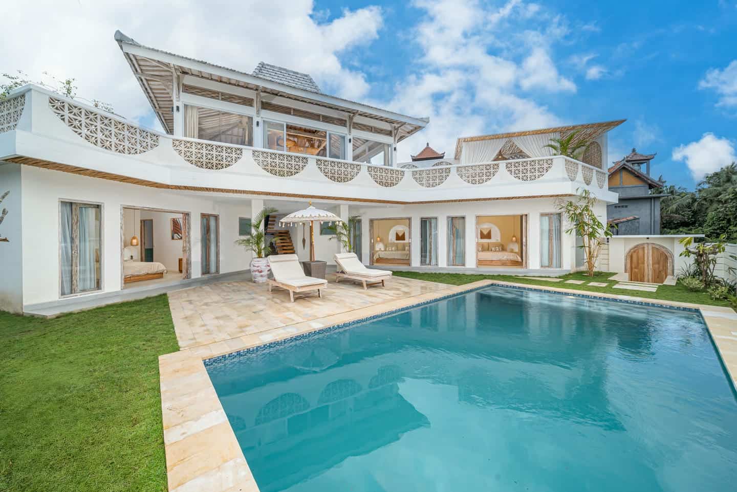 Modern villa with pool and patio on sunny day.