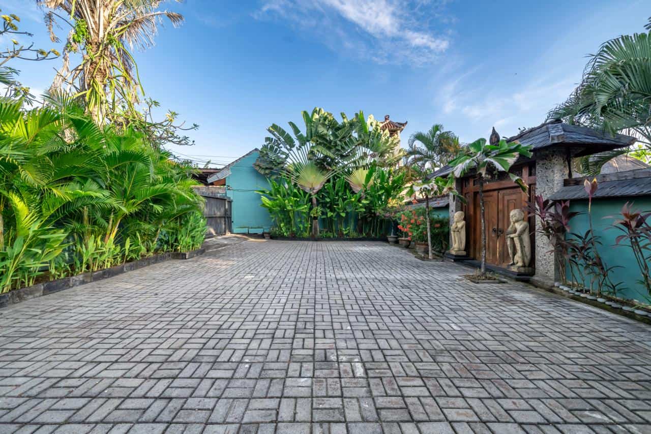 Tropical courtyard with tall plants and stone statues.