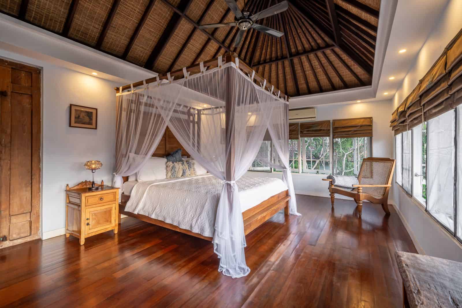 Cozy bedroom with canopy bed and wooden floor.
