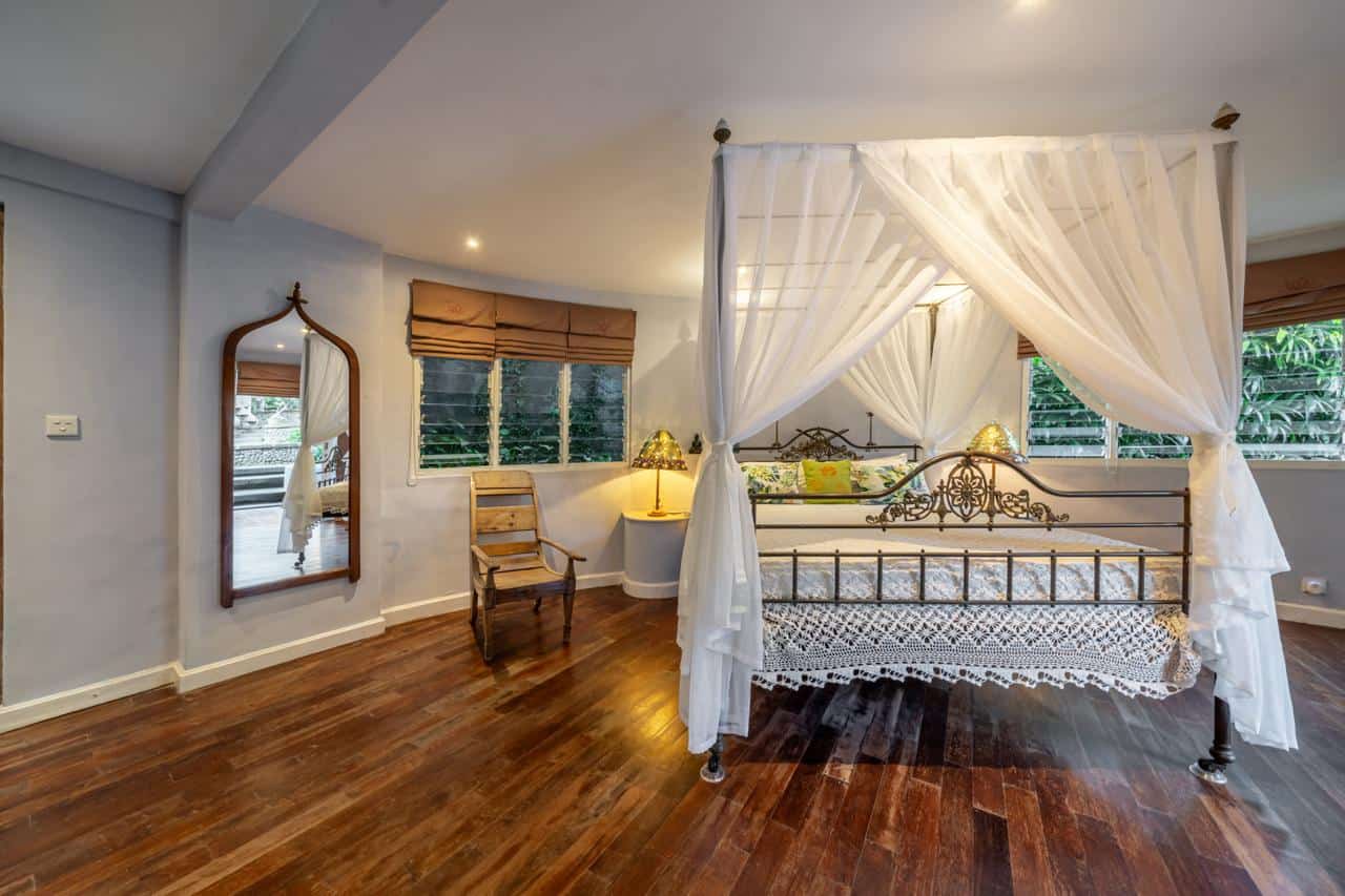 Cozy bedroom with canopy bed and wooden floors.