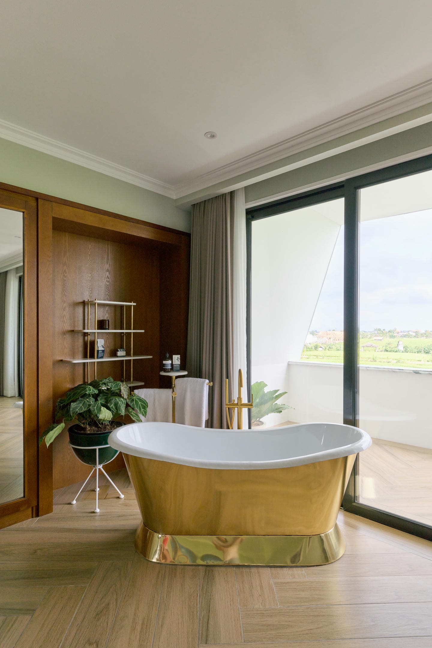 Luxurious bathroom with gold bathtub and large window.