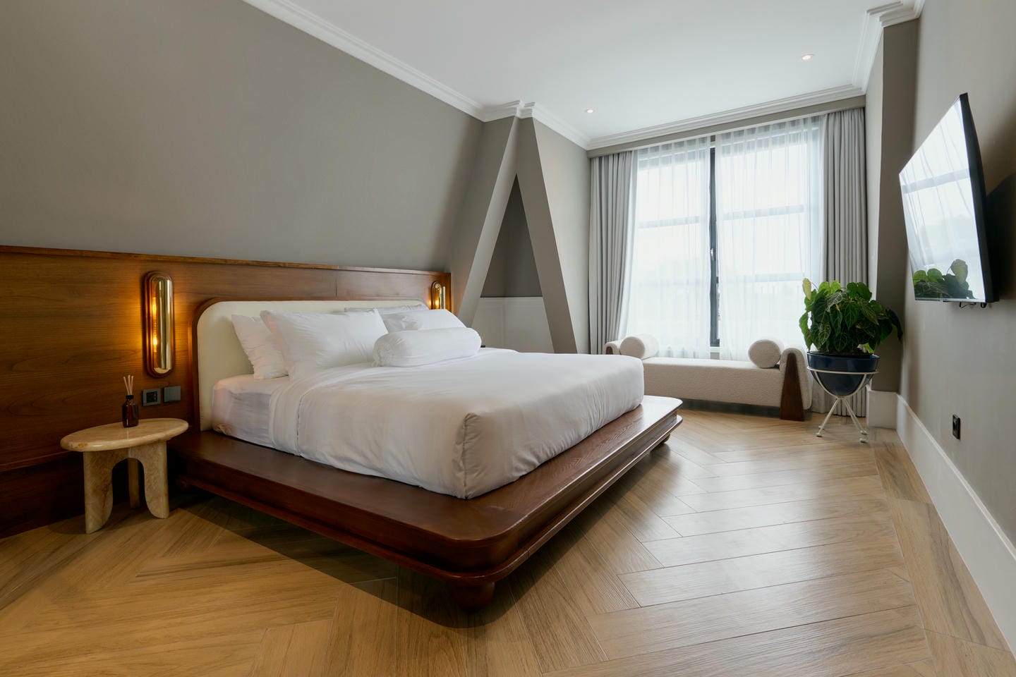 Modern bedroom with wooden flooring and large window.