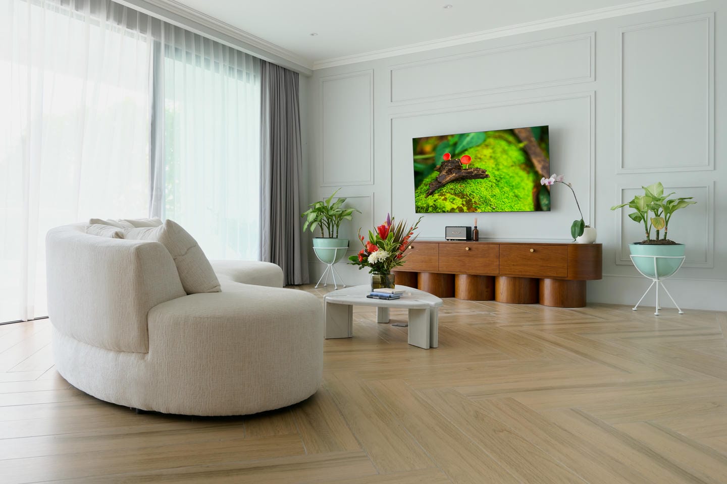 Modern living room with TV and plants.
