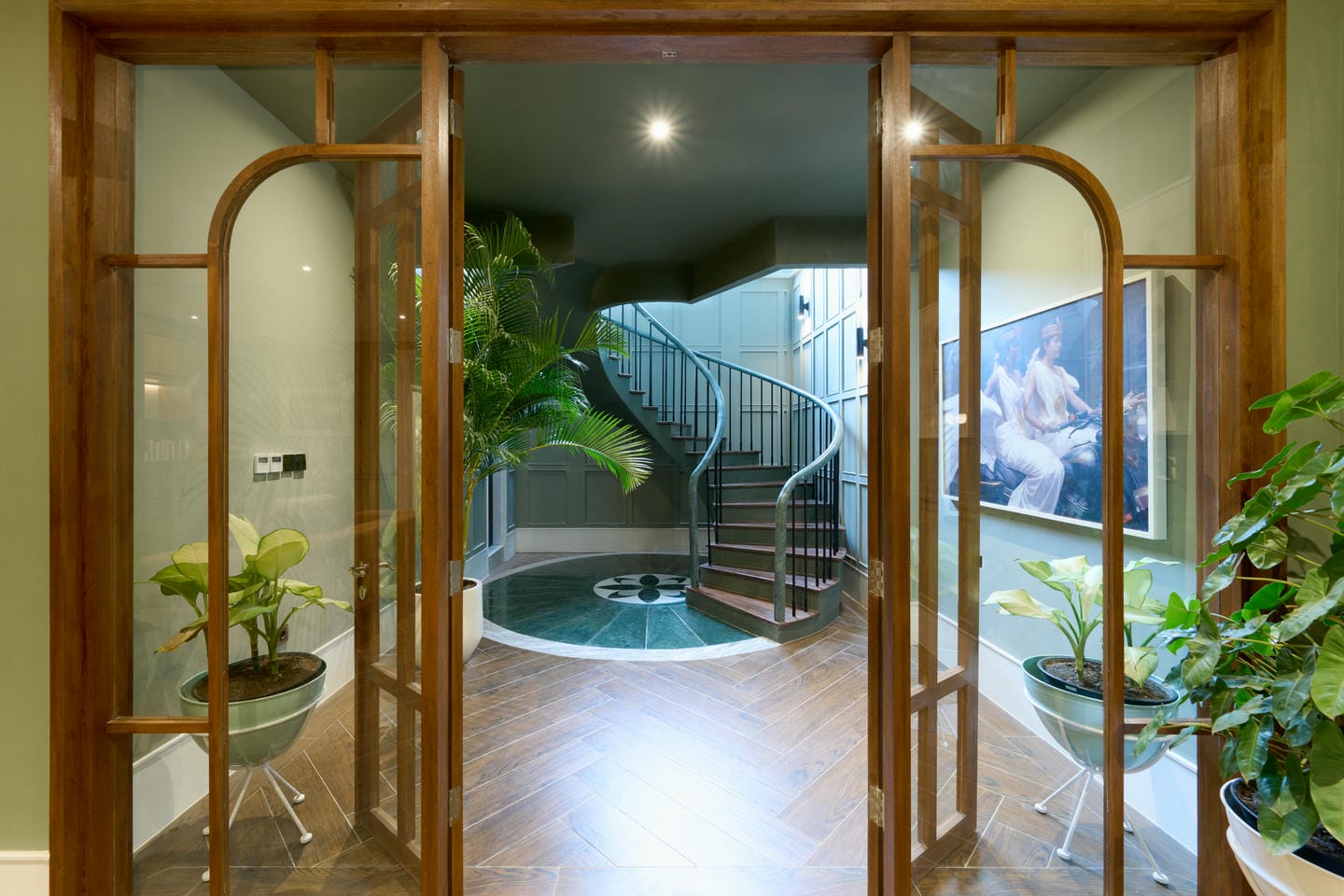 Modern foyer with spiral staircase and plants.