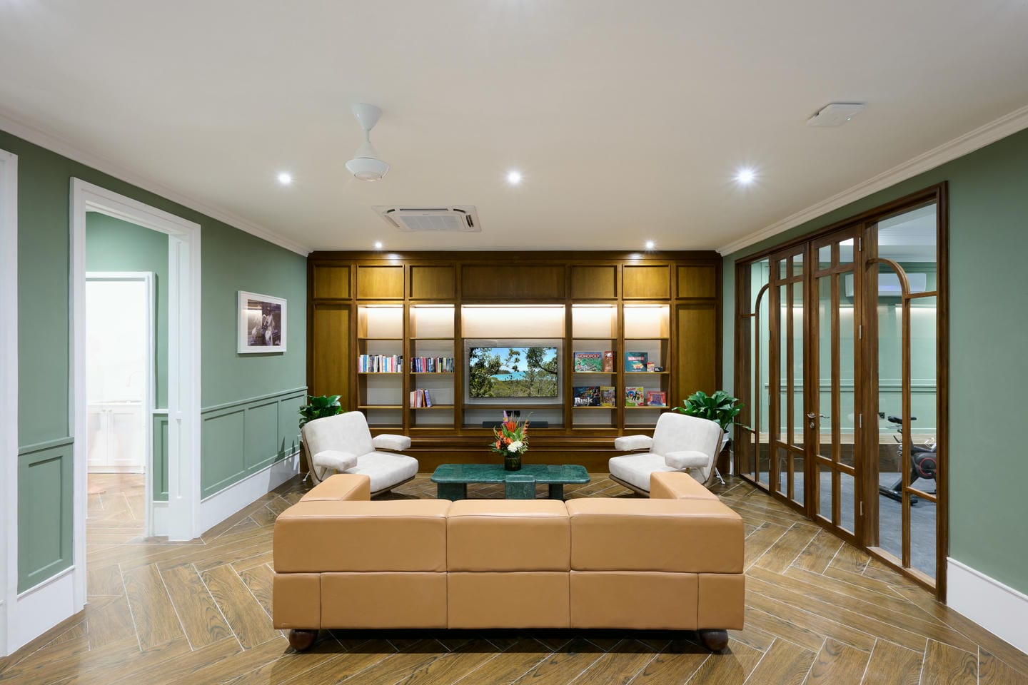 Modern green lounge with bookshelf and seating area.