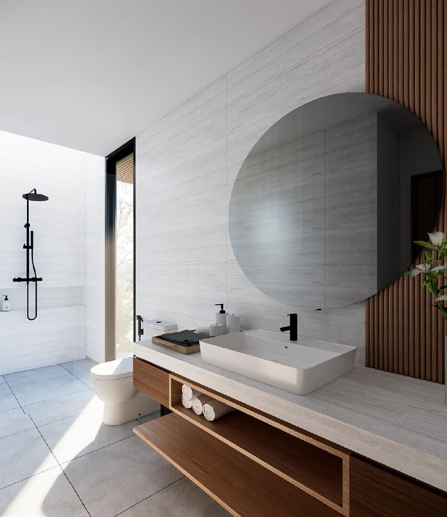 Modern bathroom with round mirror and wooden vanity.