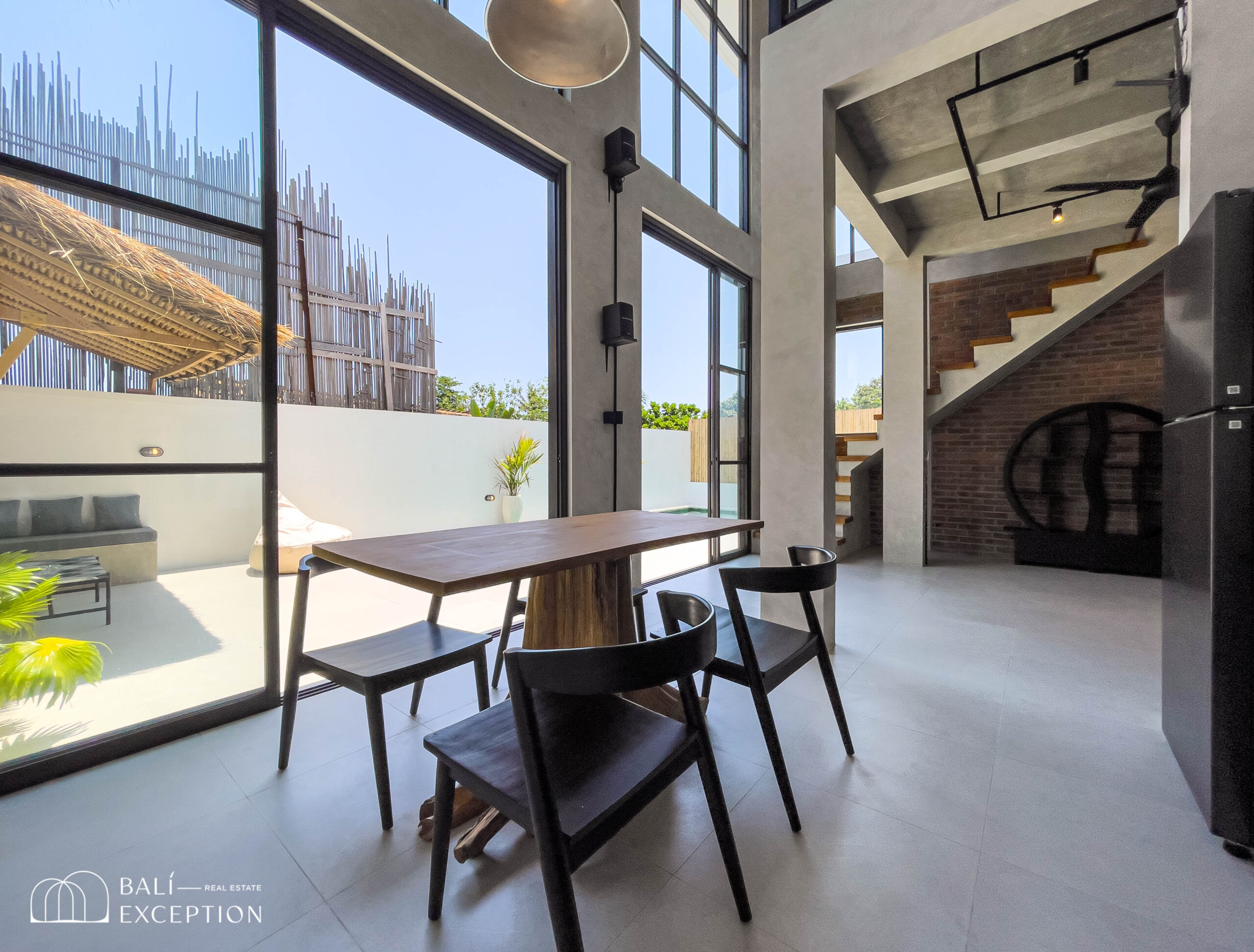 Modern dining area with glass walls and staircase.
