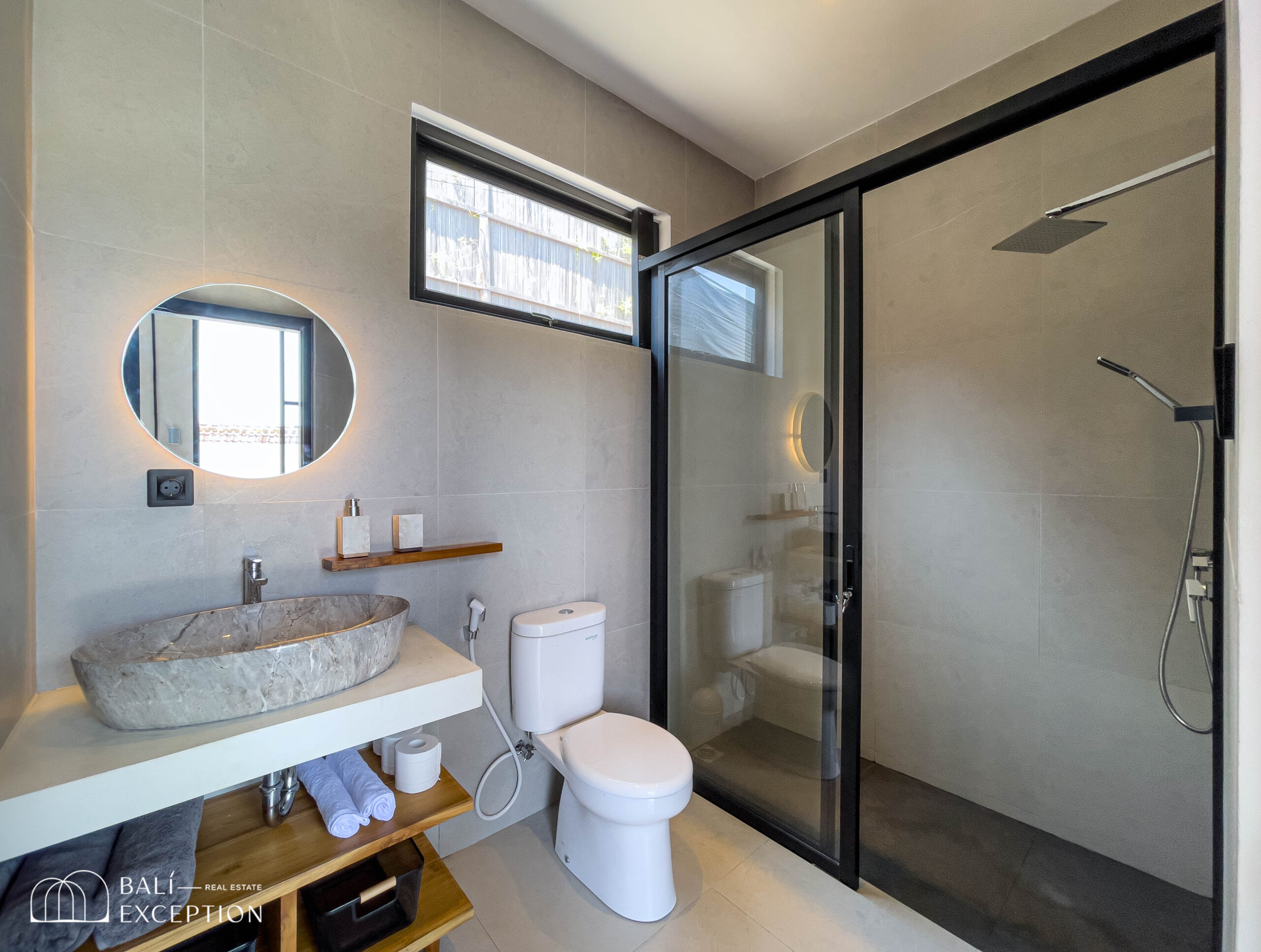 Modern bathroom with round mirror and glass shower.