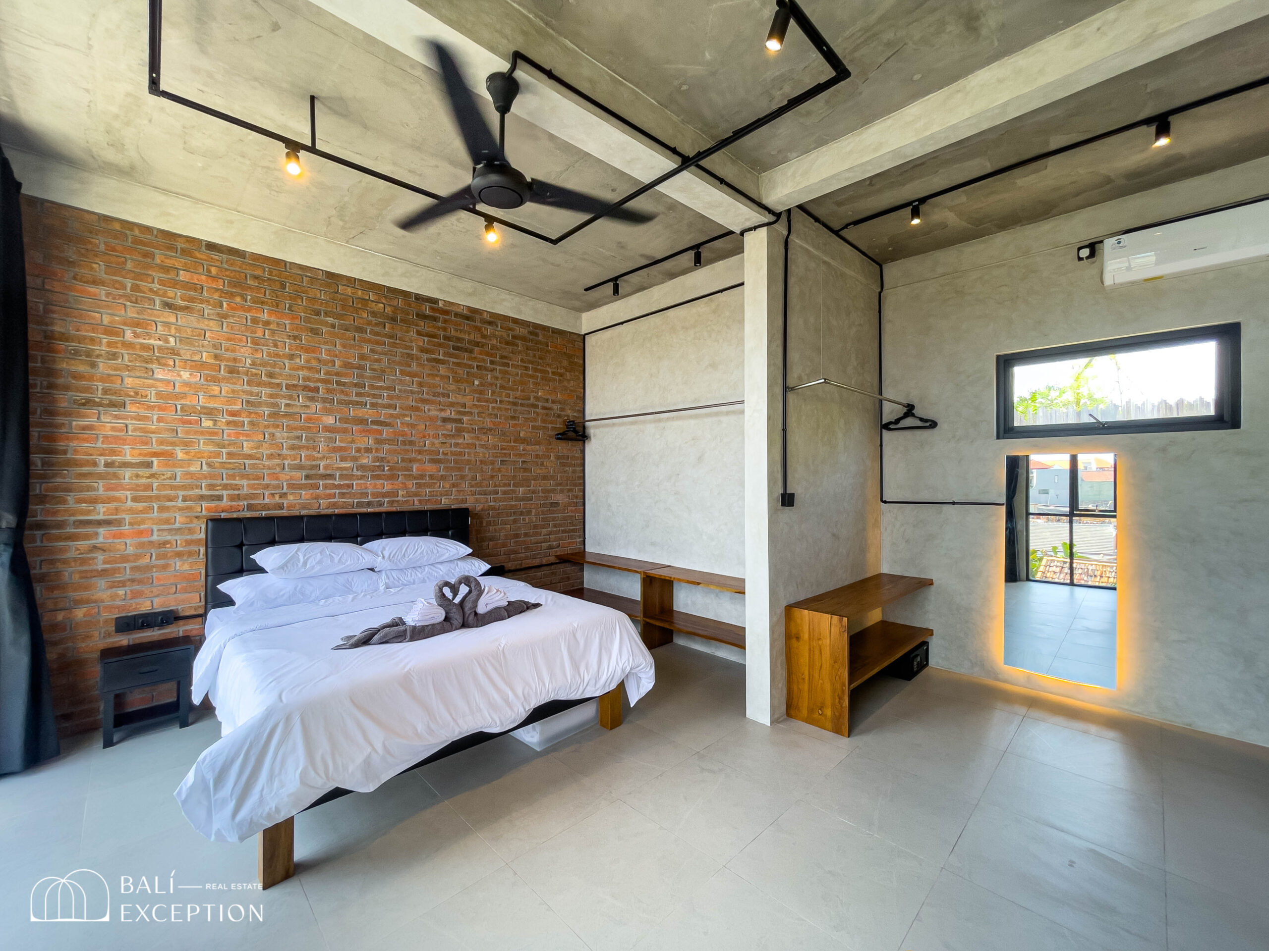Modern bedroom with brick wall and ceiling fan.