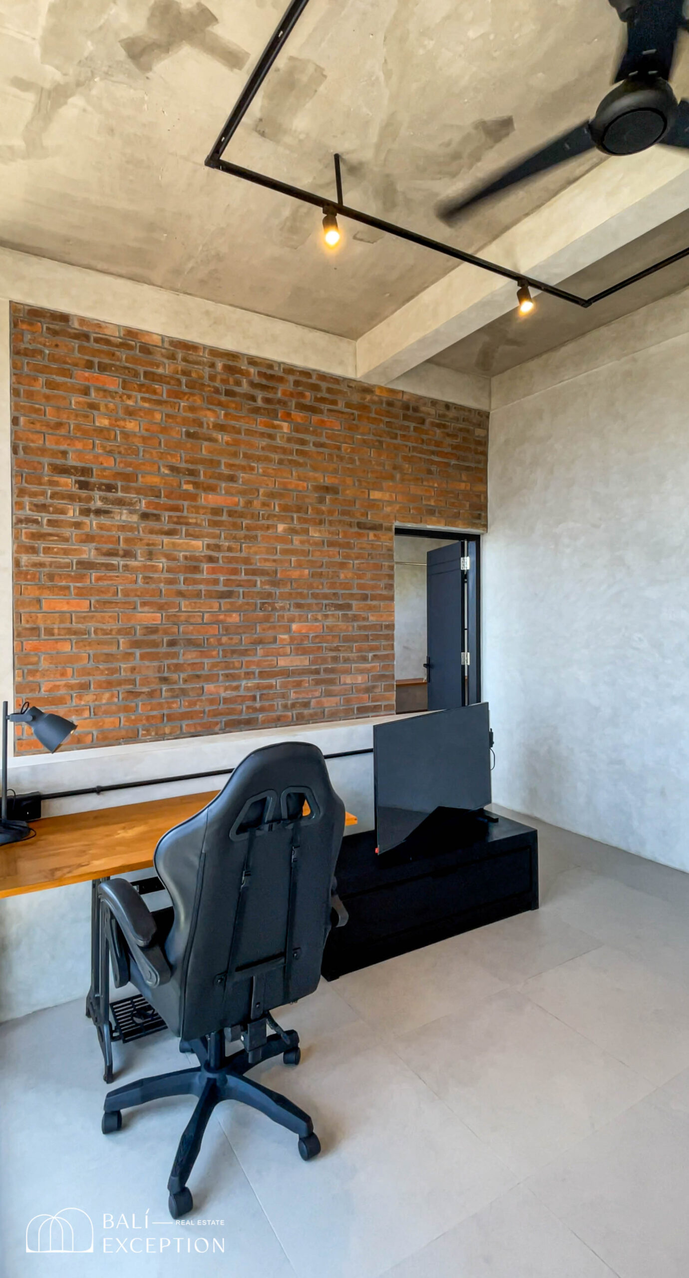 Modern office with brick wall and desk setup.
