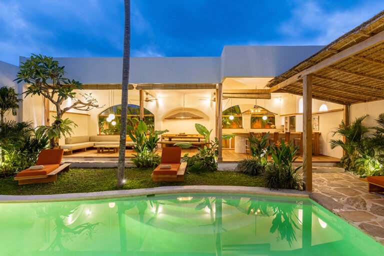 Luxurious villa with pool and tropical garden at night.