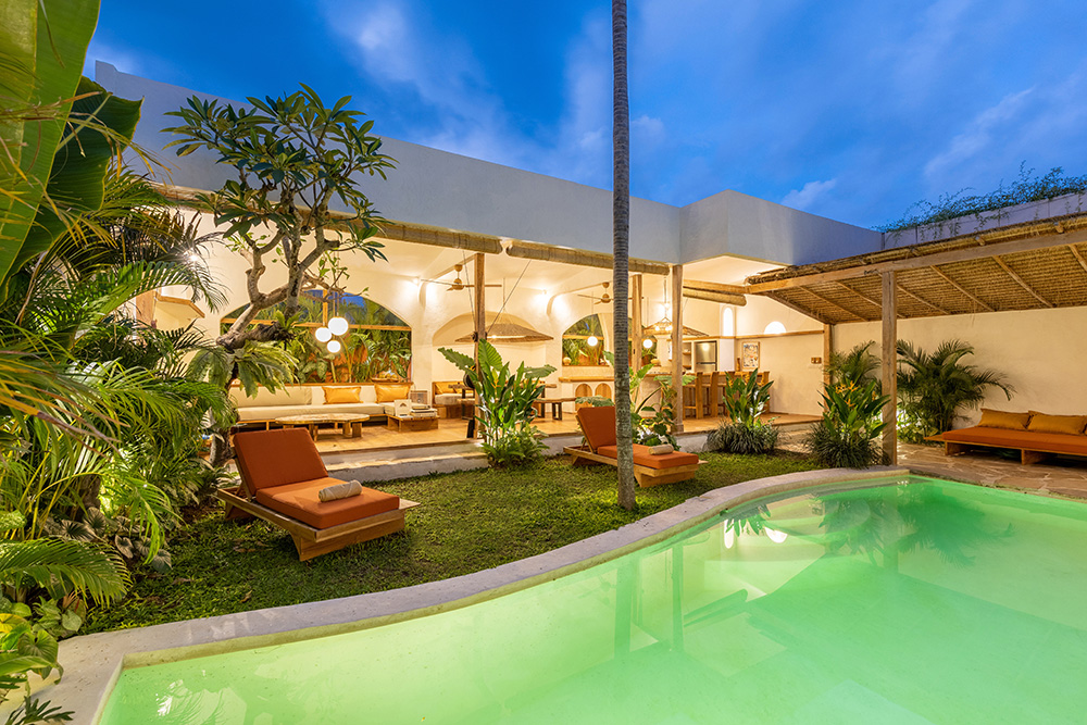 Tropical villa with pool and lush garden at dusk.