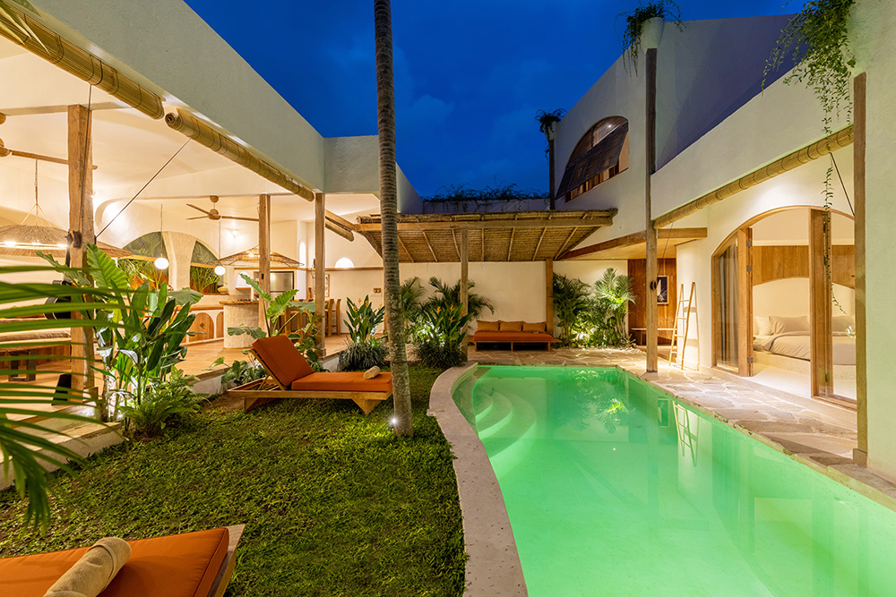 Modern house with illuminated pool and greenery.