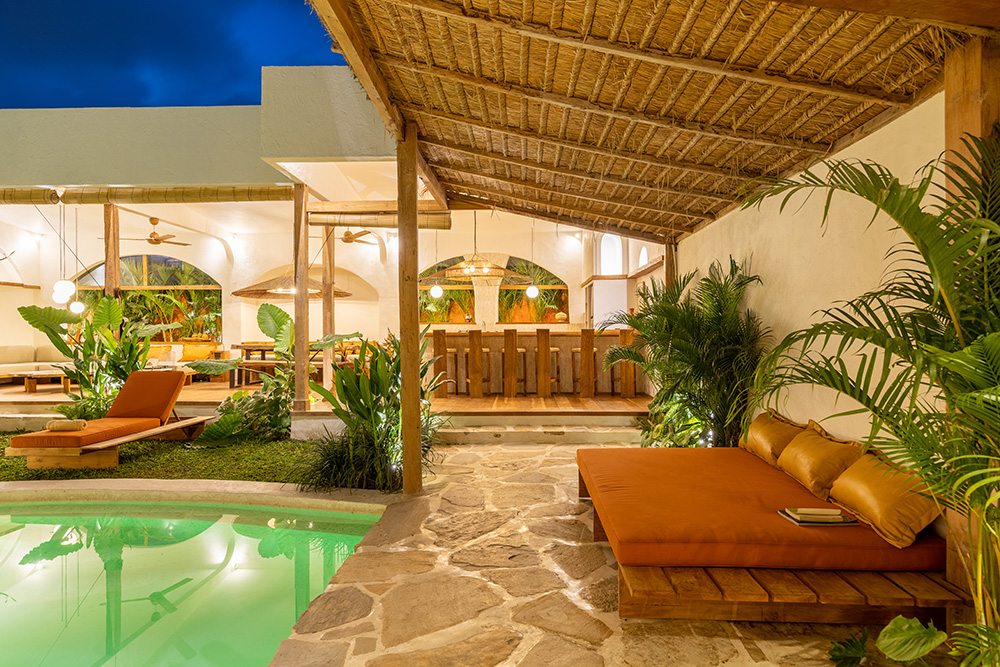 Luxurious tropical poolside lounge with seating and greenery.