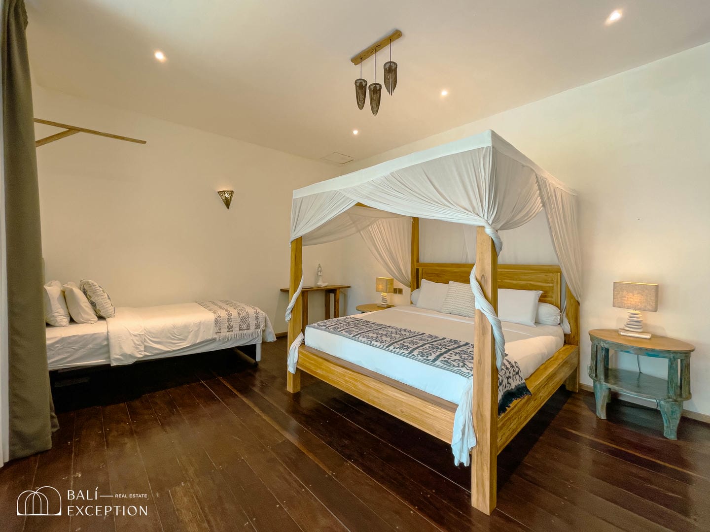 Spacious bedroom with canopy bed and wooden floor.