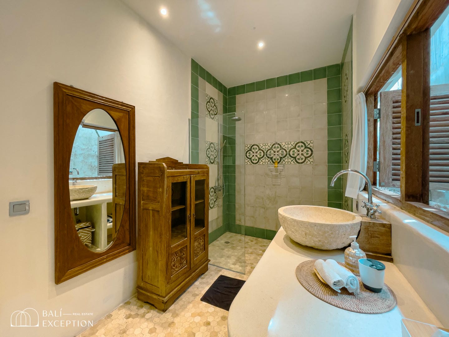 Elegant bathroom with green tile accents and wood cabinet.