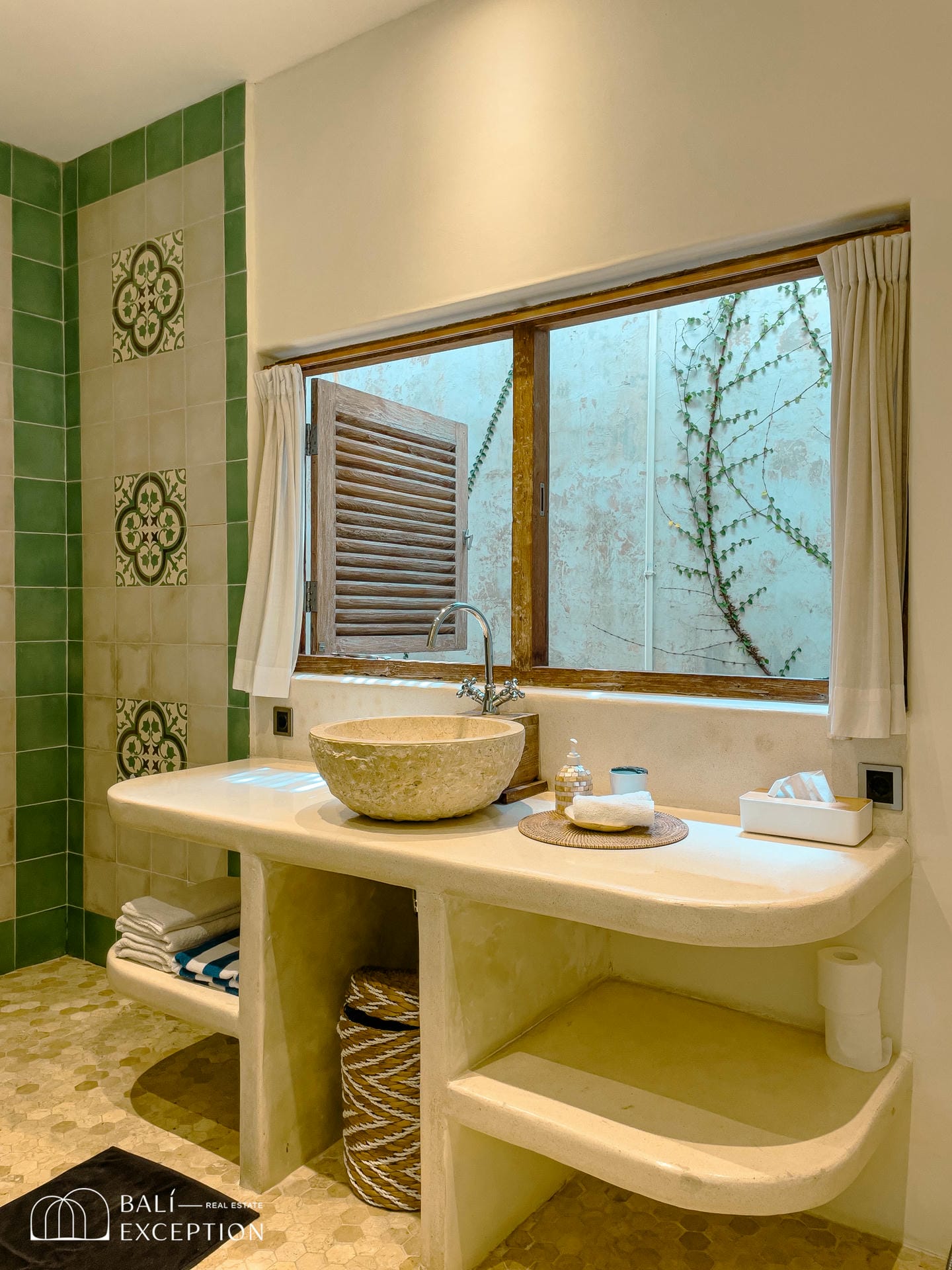 Elegant bathroom with natural stone sink and green tiles.