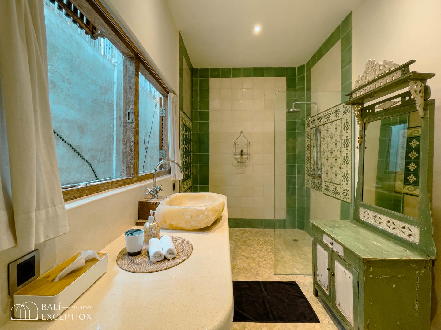 Rustic bathroom with green tiles and natural sink.