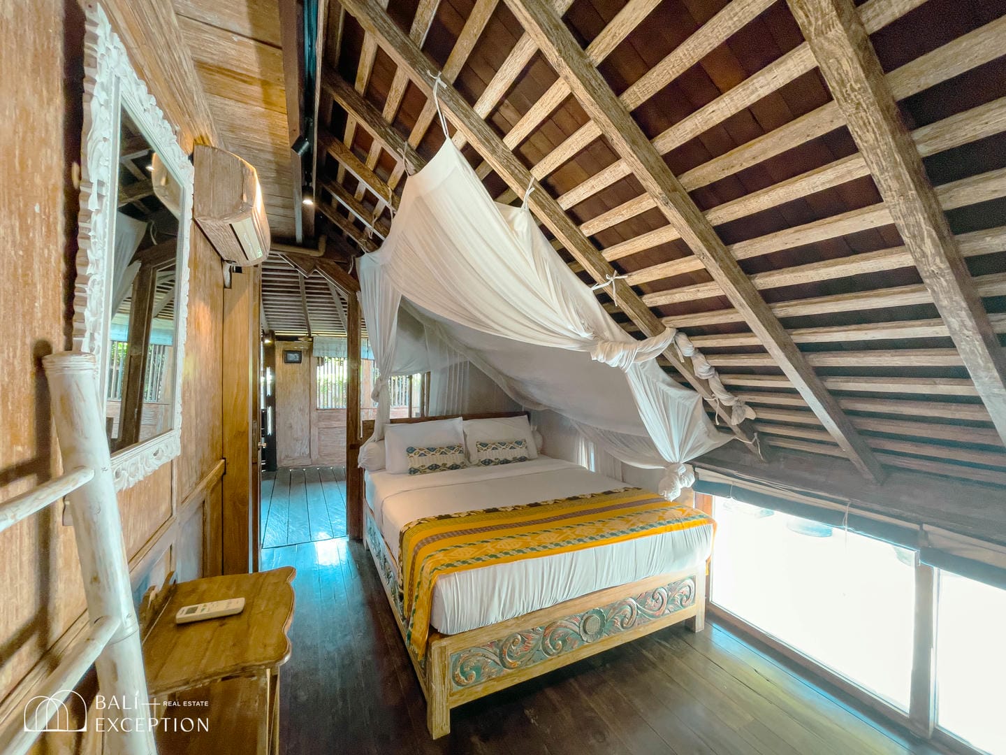 Rustic bedroom with wooden beams and canopy bed.