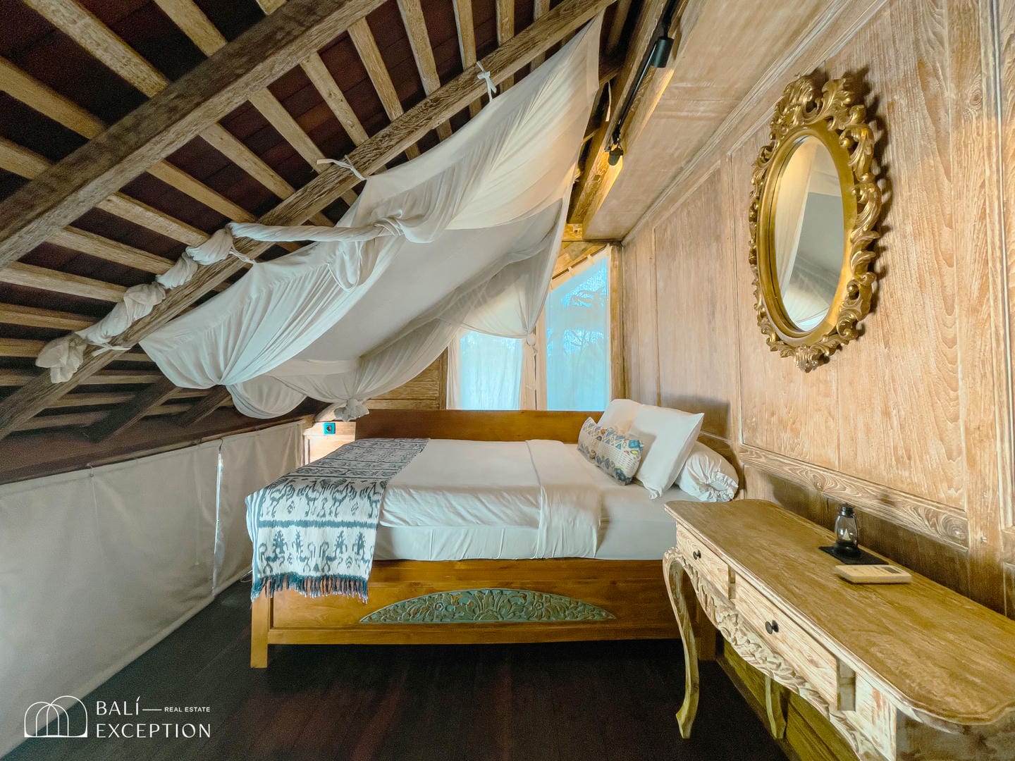 Cozy attic bedroom with wooden bed and mirror.
