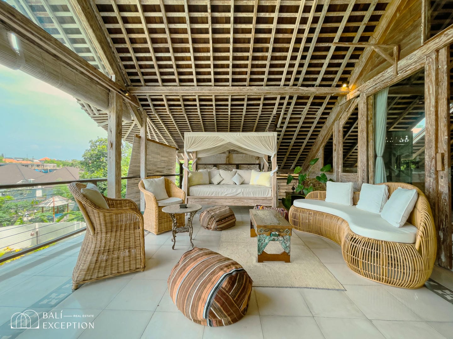 Cozy outdoor patio with wicker furniture and canopy bed.