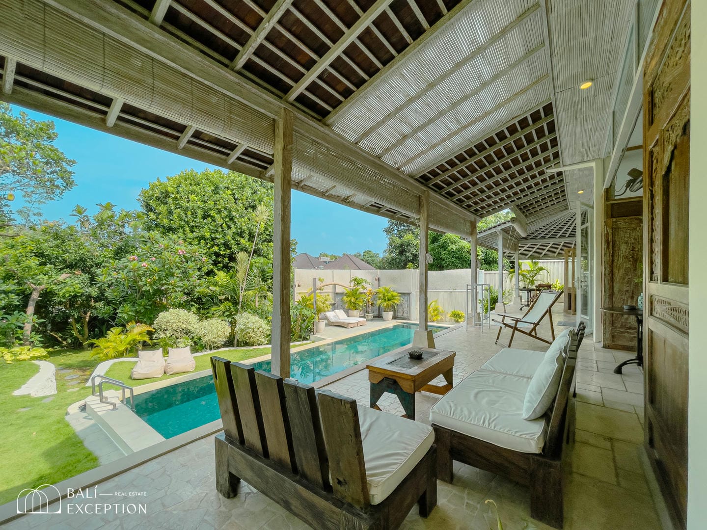 Tropical villa patio with pool and garden view.