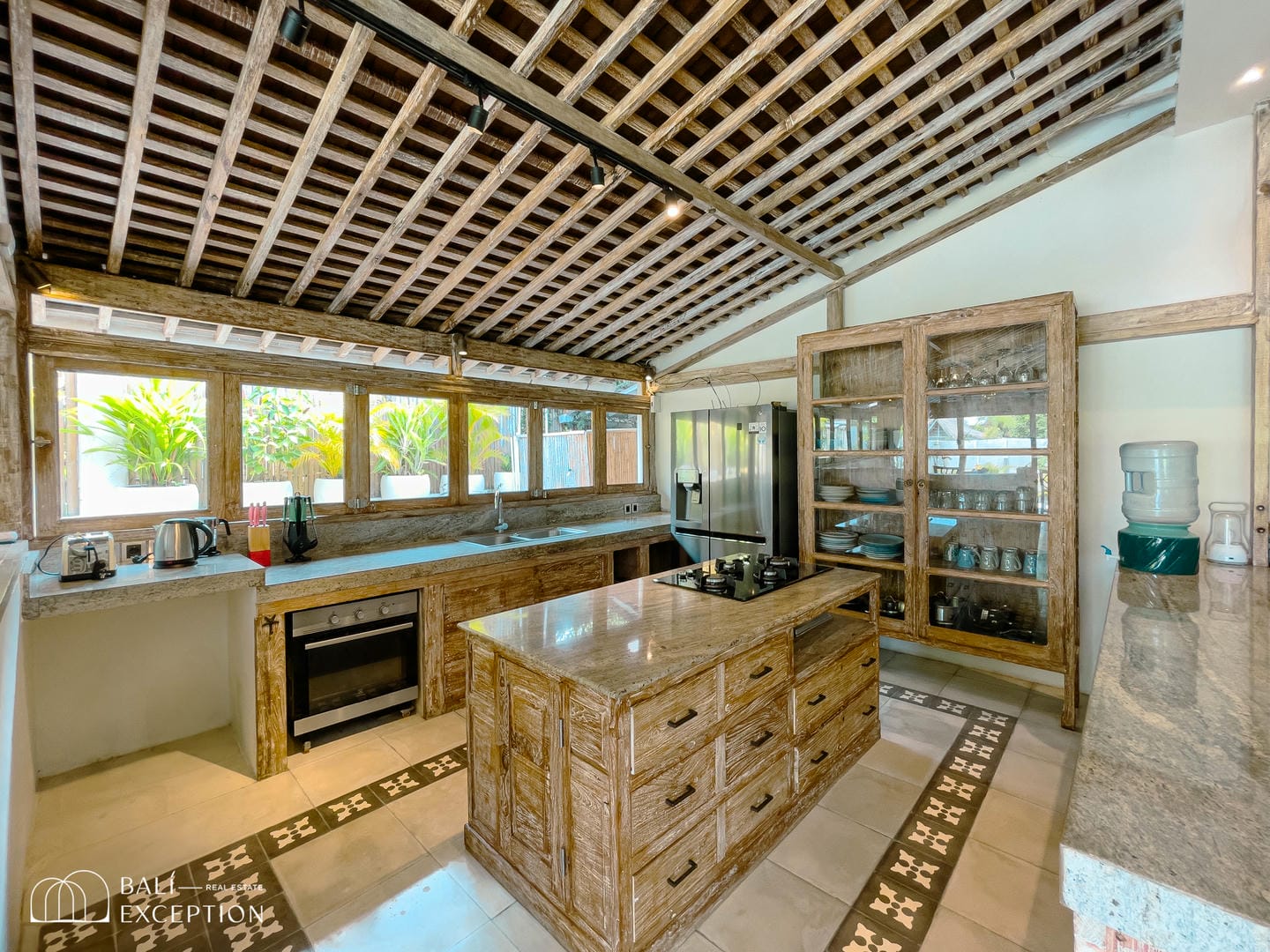 Rustic kitchen with natural wood accents and large windows.