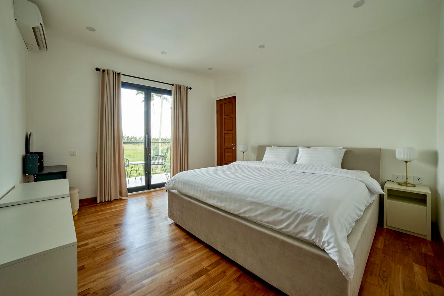 Modern bedroom with large bed and balcony view.