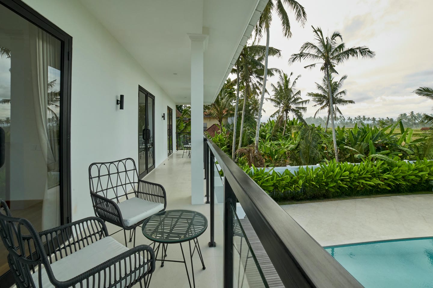 Balcony with chairs, pool, tropical garden view