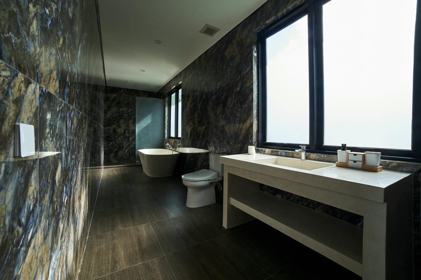 Modern bathroom with bathtub and marble walls.