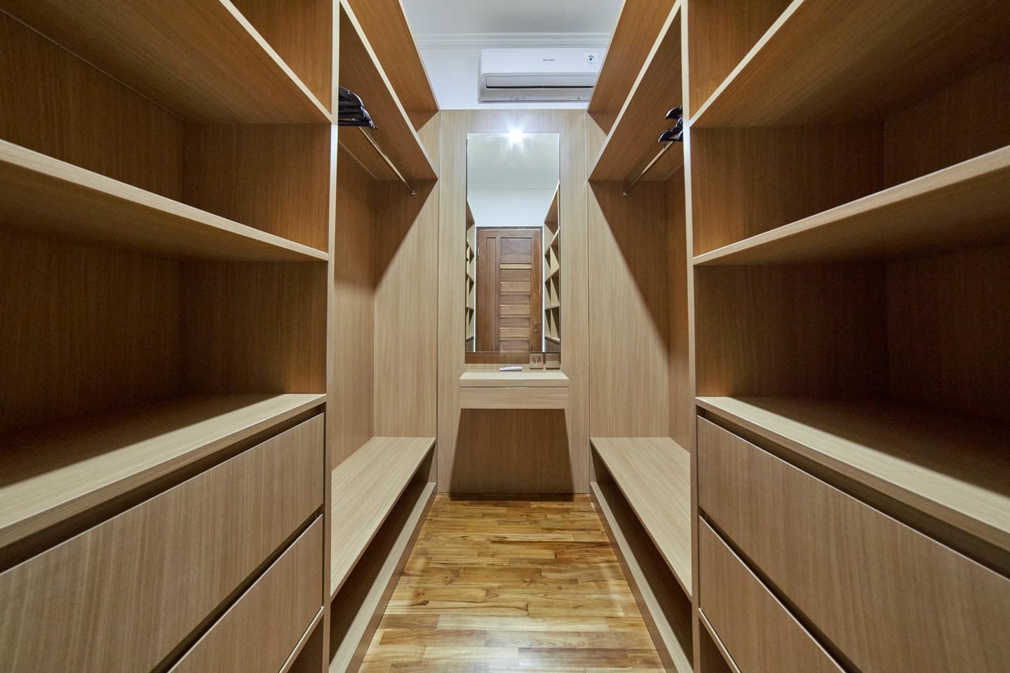 Spacious wooden walk-in closet with mirror.
