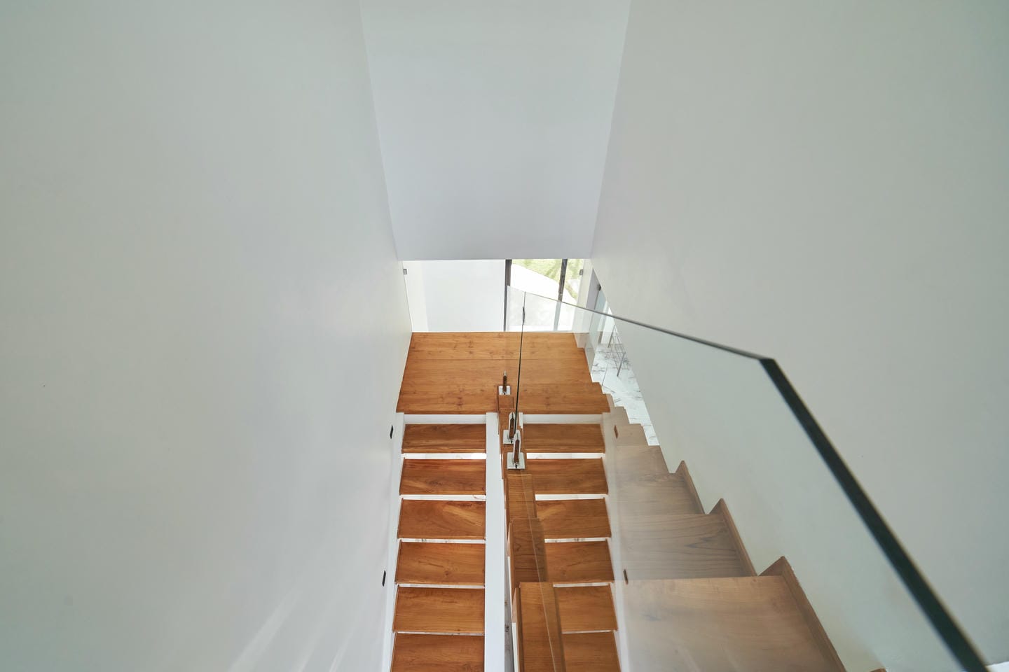 Modern wooden staircase with white walls.