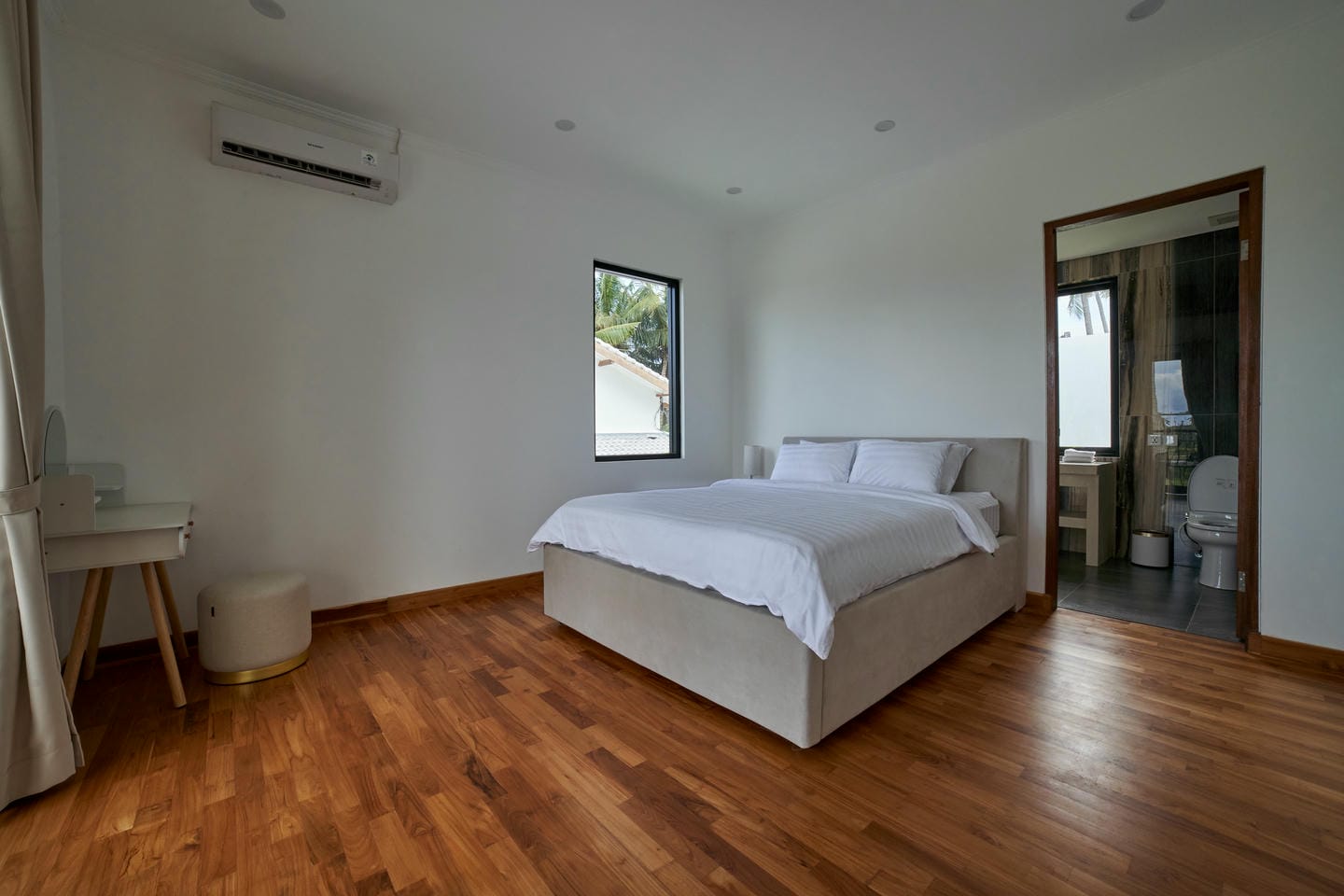 Modern bedroom with wooden floor and ensuite bathroom.