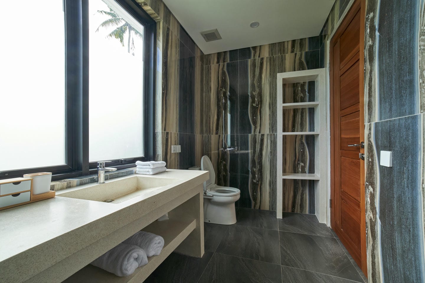Modern bathroom with large window and marble walls.
