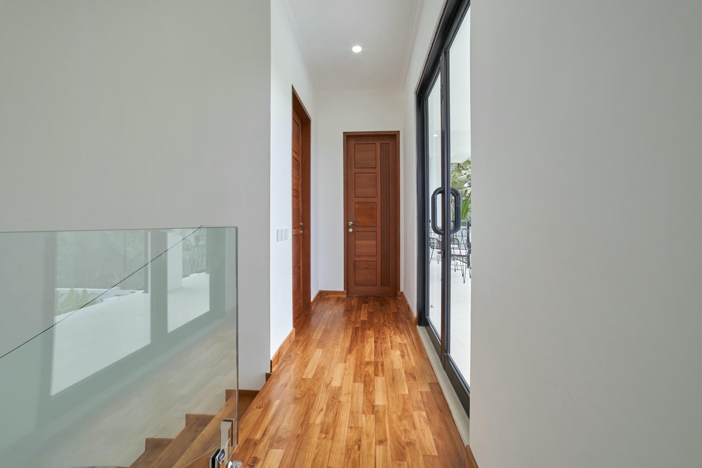 Modern hallway with wooden flooring and glass door.
