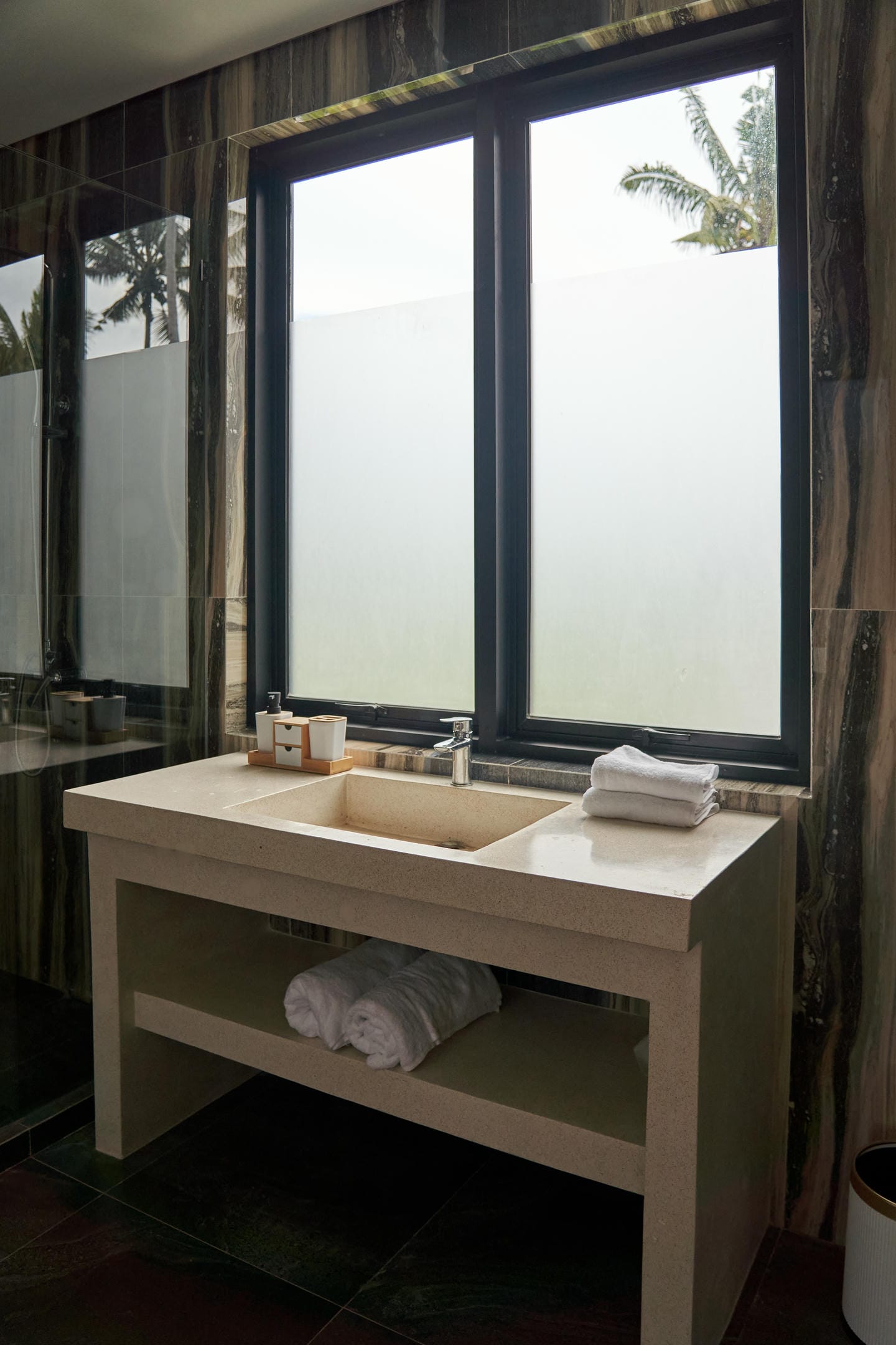 Modern bathroom with stone sink and window view.