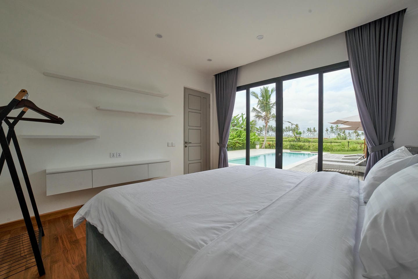Modern bedroom overlooking pool and garden view.