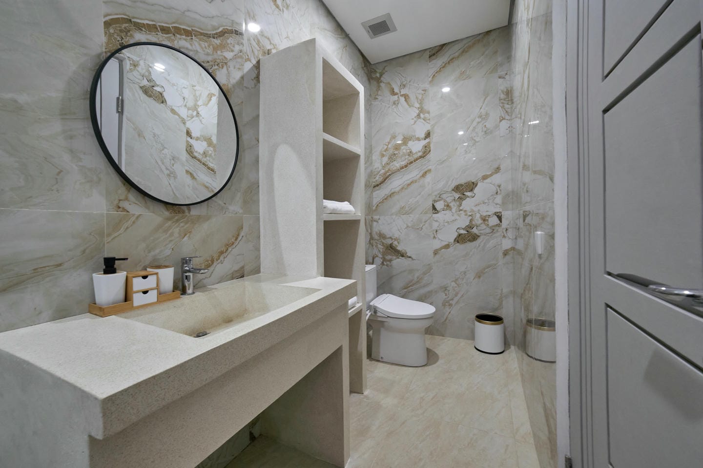 Modern bathroom with marble decor and round mirror.