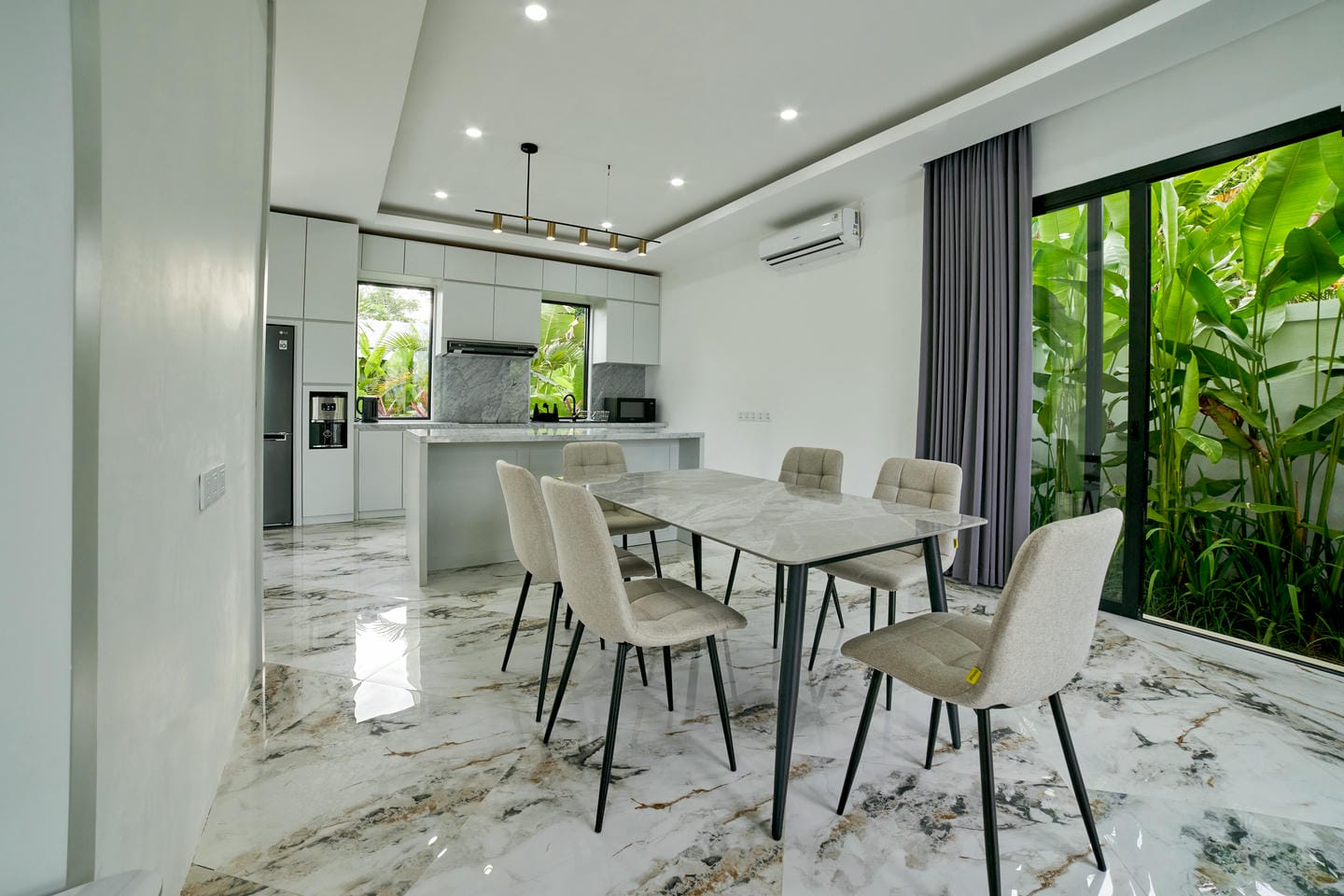Modern kitchen with marble floors and dining area.