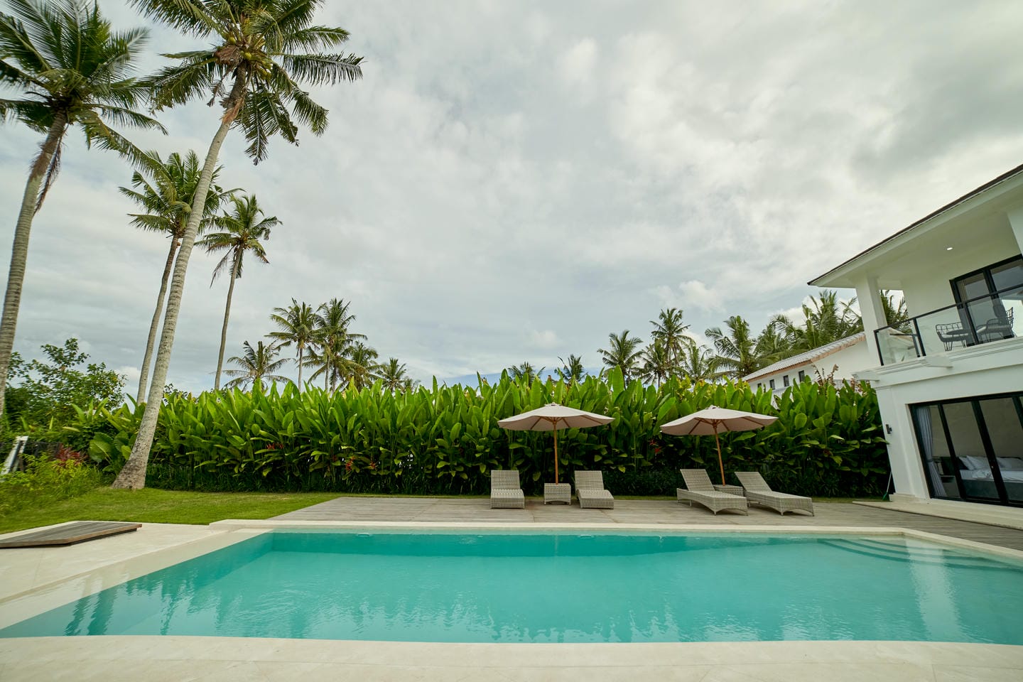 Tropical poolside with loungers and palm trees.