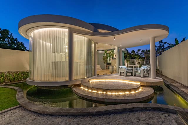 Modern circular house with glass walls at dusk.