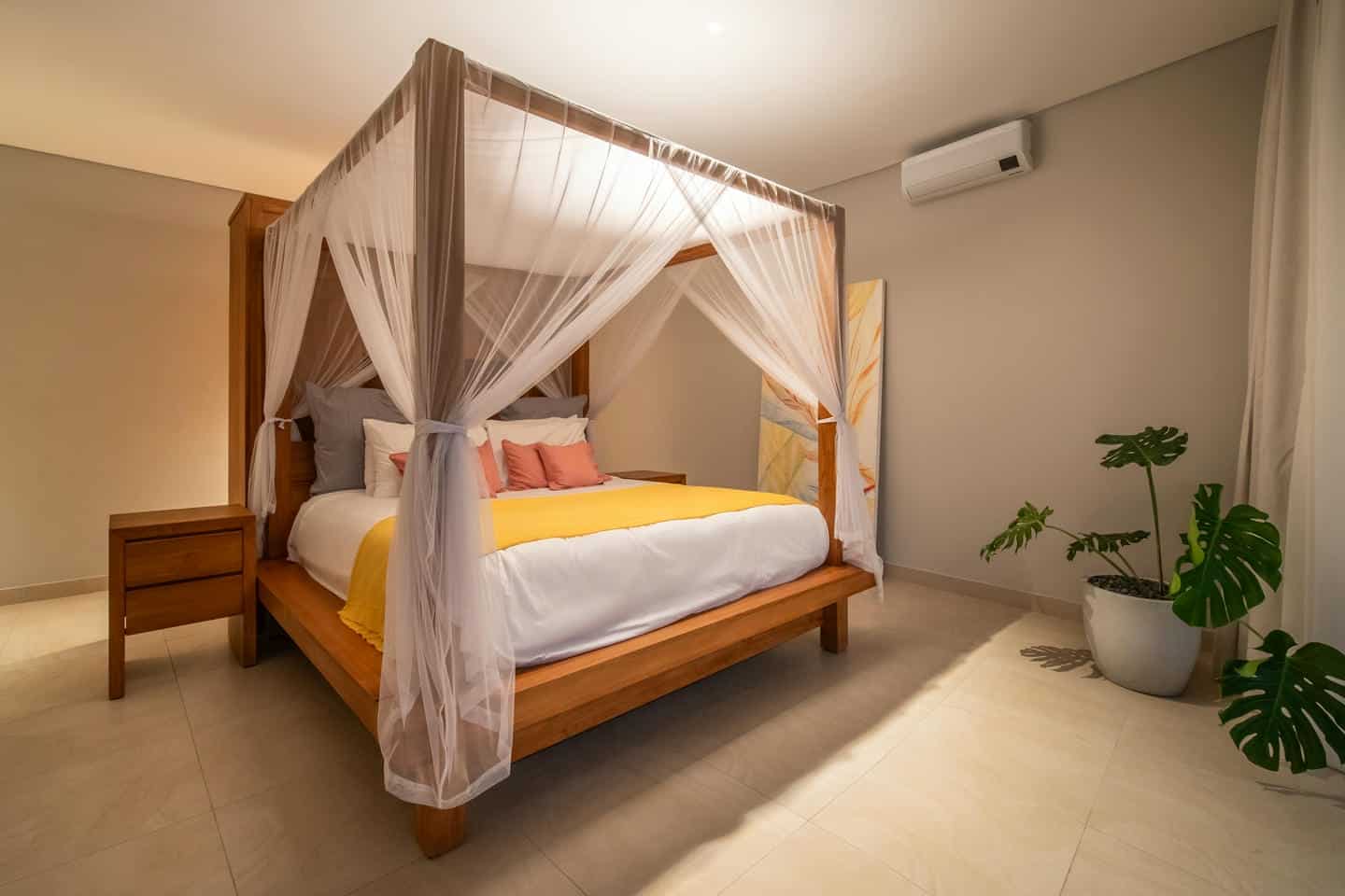 Cozy bedroom with canopy bed and plants.
