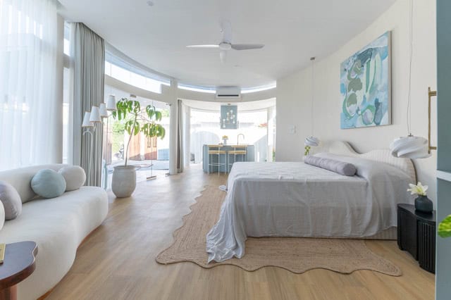 Spacious modern bedroom with large windows and plants.