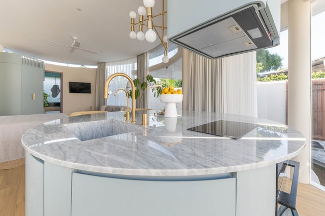 Modern kitchen with marble island and gold faucet.