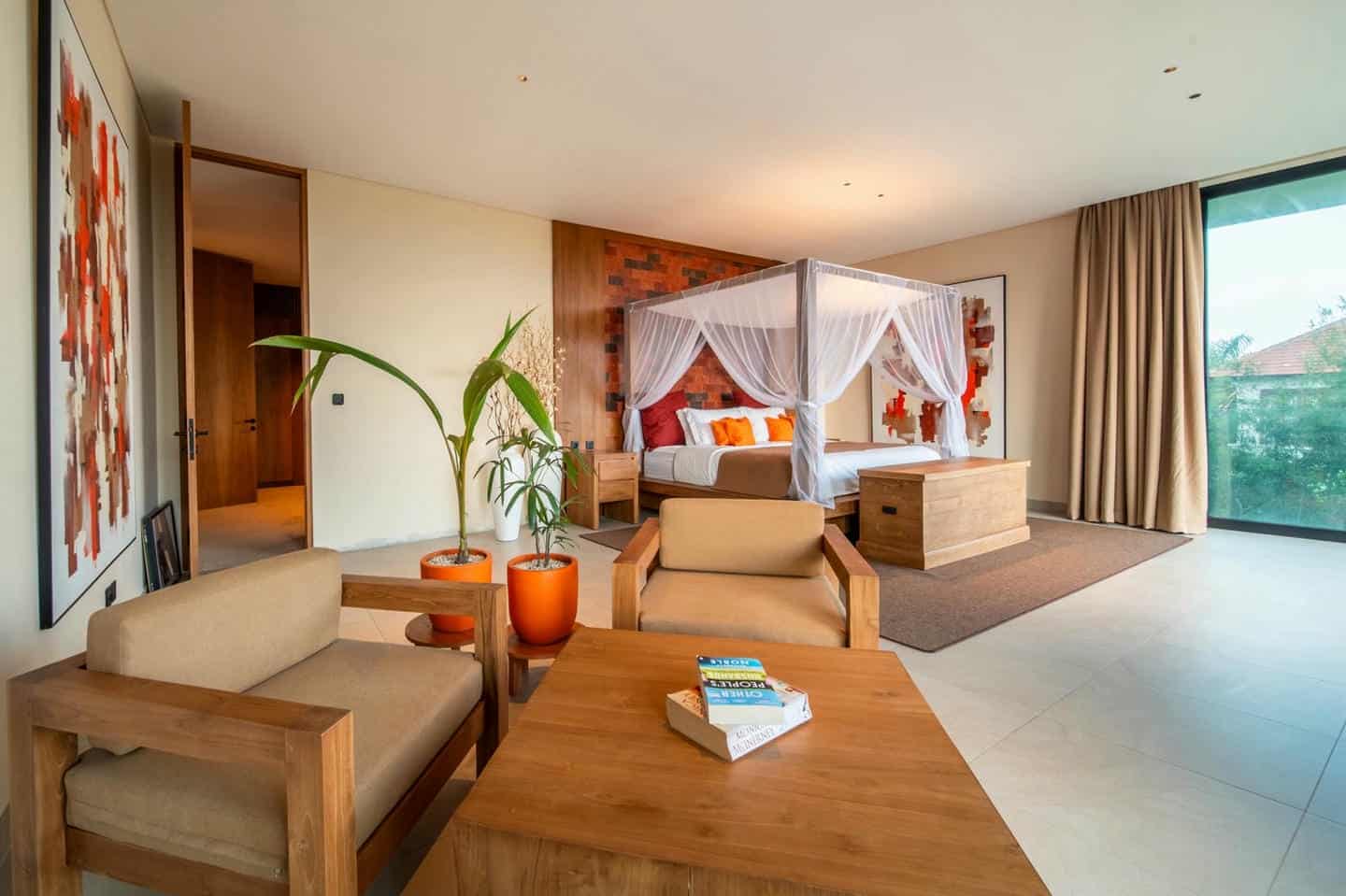 Modern bedroom with canopy bed and seating area.