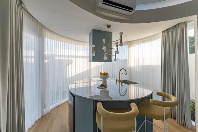 Modern kitchen with round island and chandeliers.