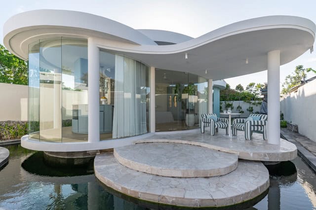 Modern glass-walled house with outdoor seating.